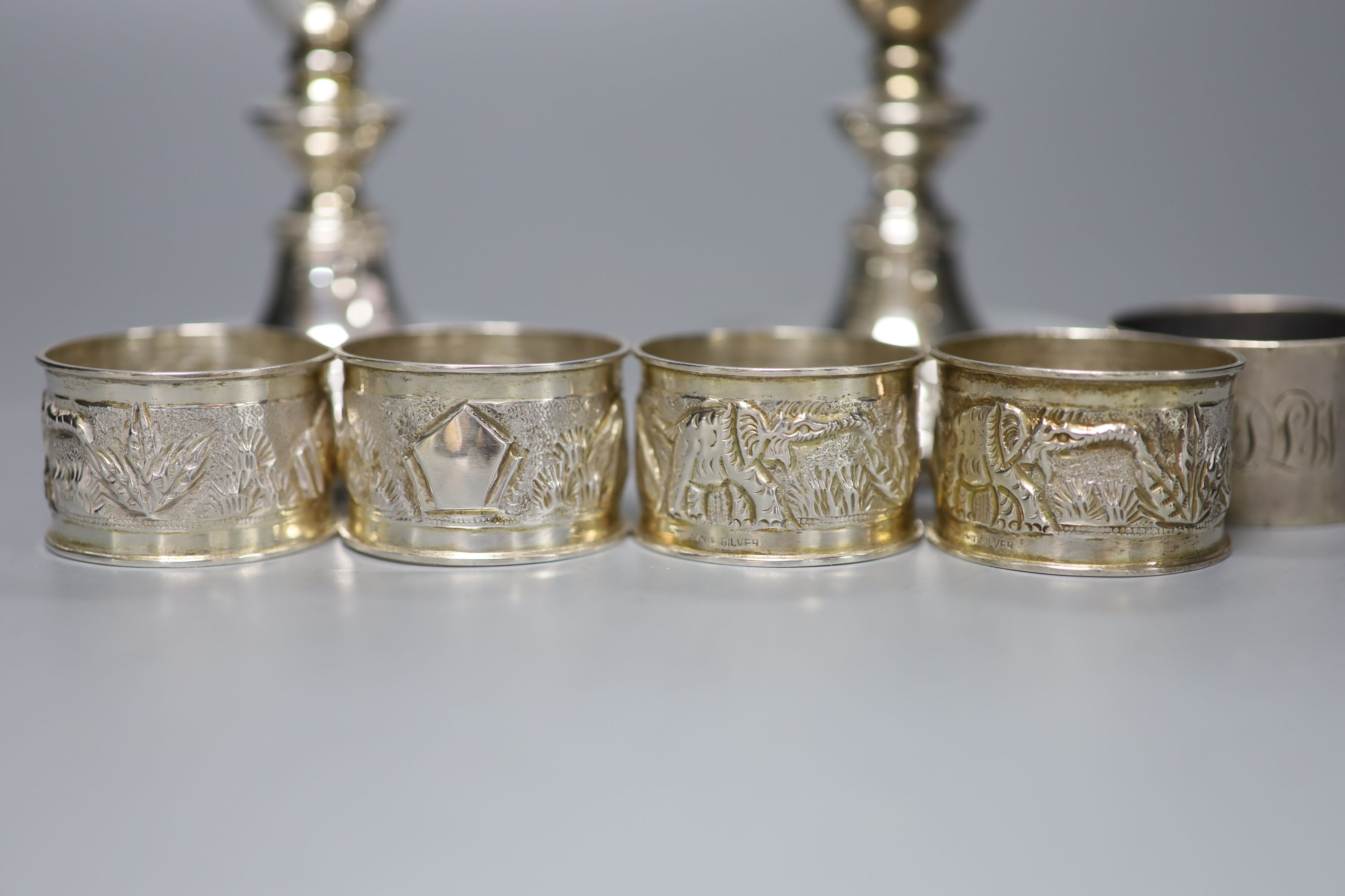 A pair of modern silver dwarf candlesticks, 12cm, a silver napkin ring and four sterling napkin rings.
